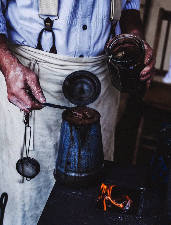 Skilled chef pouring sauce into a jar over a stove in a professional kitchen.