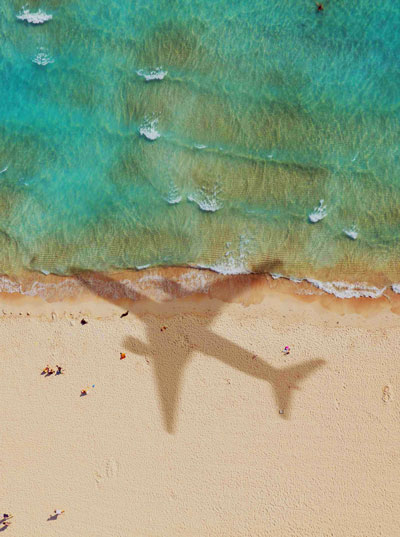 Softinator Dynamics Shadow of an airplane over the beach from above.