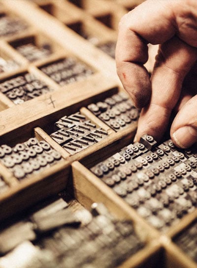 Softinator Dynamics Hand selecting letterpress type in a traditional printing setup.