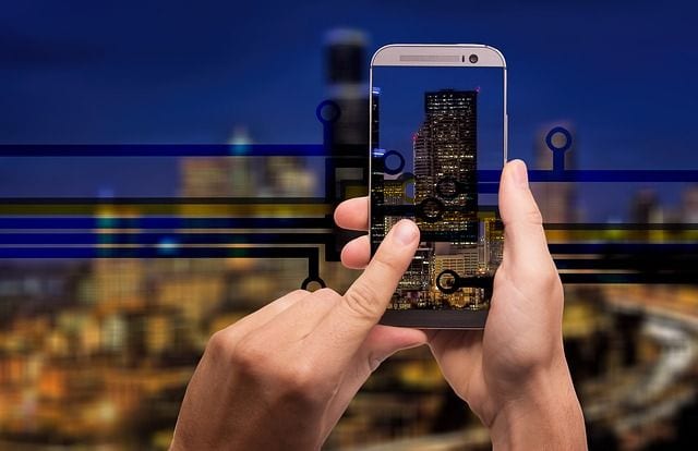 Person controlling smart home devices with smartphone at night.