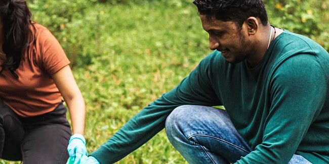 Two people planting trees outdoors to promote sustainable technology practices.
