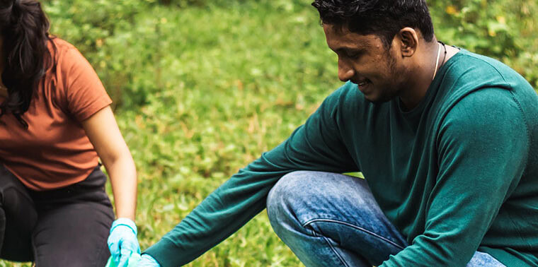 Two people planting trees outdoors to promote sustainable technology practices.
