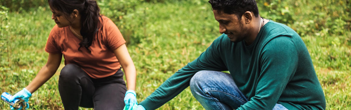 Two people planting trees outdoors to promote sustainable technology practices.