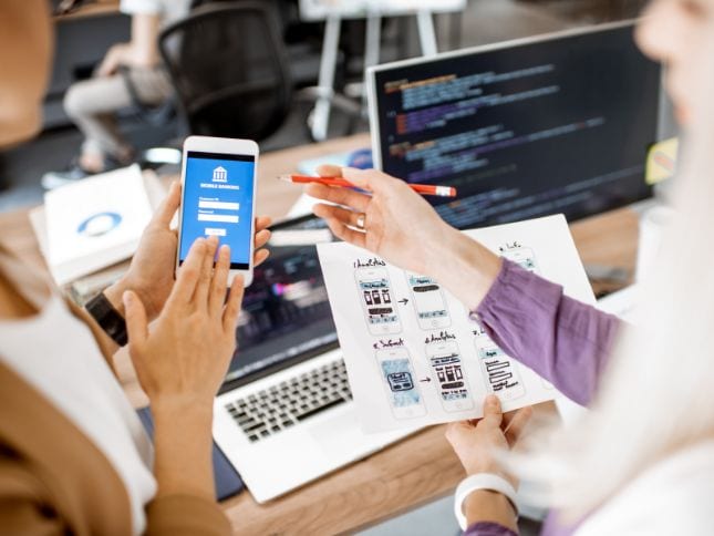 Team working on Android app development with smartphones and laptops.