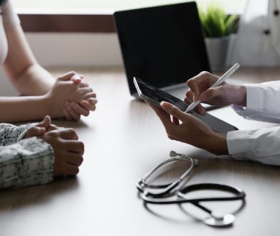 Healthcare professional using a tablet to discuss patient care with a patient.