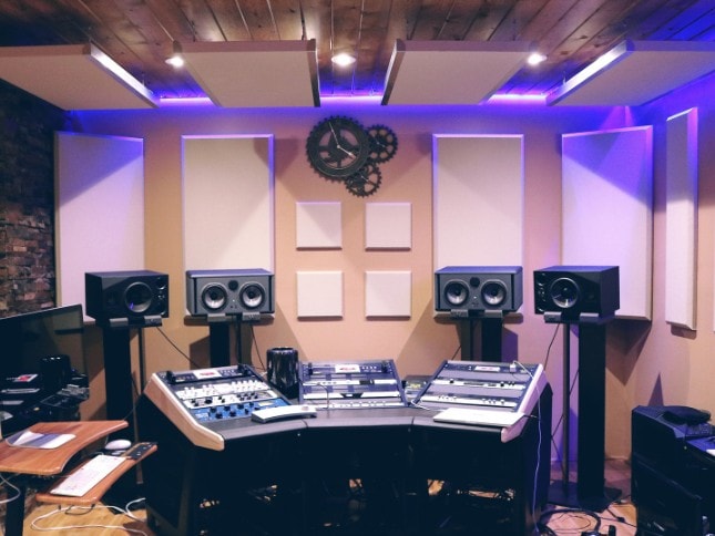 Modern music studio featuring speakers, mixing consoles, and acoustic panels for professional sound.