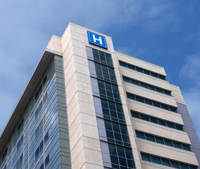Hospital building with modern architecture and glass windows under a clear blue sky.