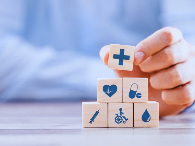 Wooden blocks with healthcare and insurance symbols, representing health coverage.
