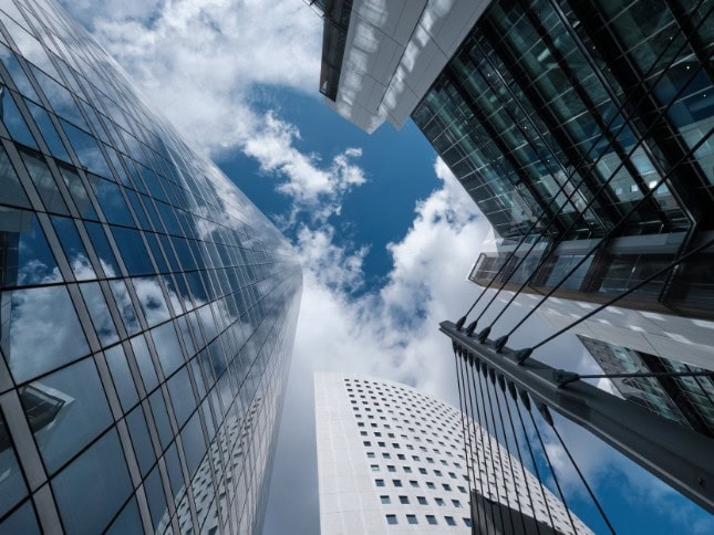 Tall glass skyscrapers reflecting the sky in a bustling city center.