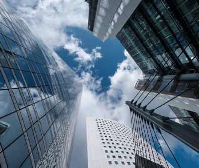 Skyscrapers with glass facades reflecting the sky and clouds.