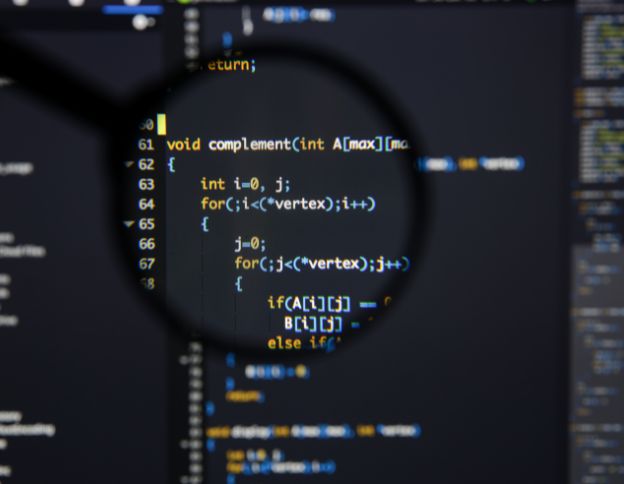 Software code on screen with magnifying glass highlighting C++ Qt application development.