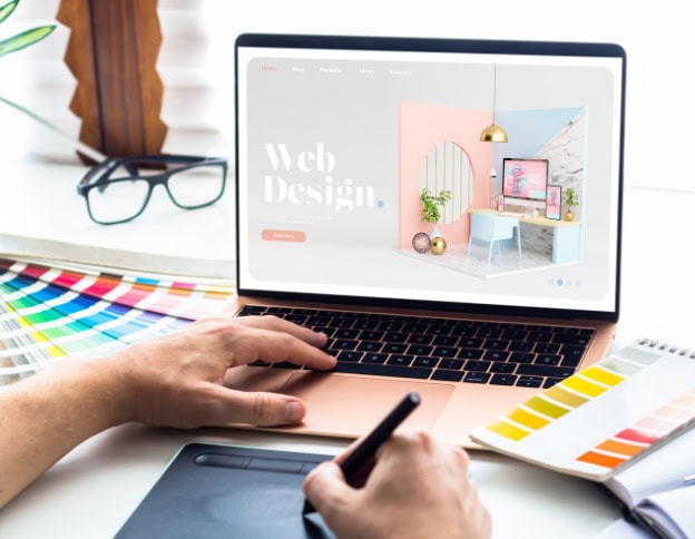 Laptop displaying modern web design with pastel colors and decor elements.