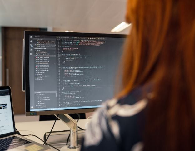 Developer coding software on a computer screen at Softinator TechLabs.