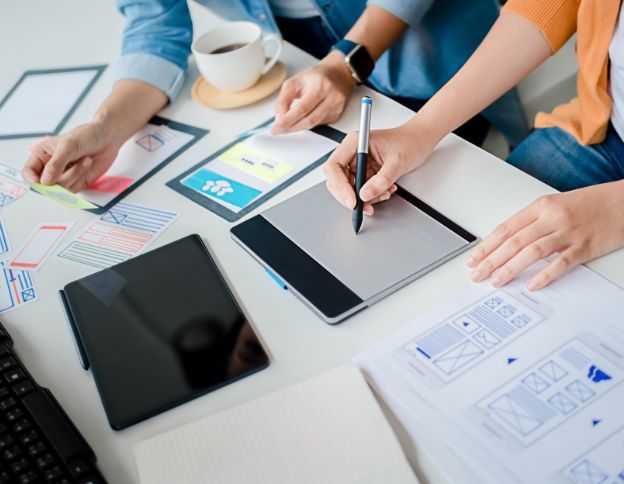 Team working on mobile app design with tablets and sketches.