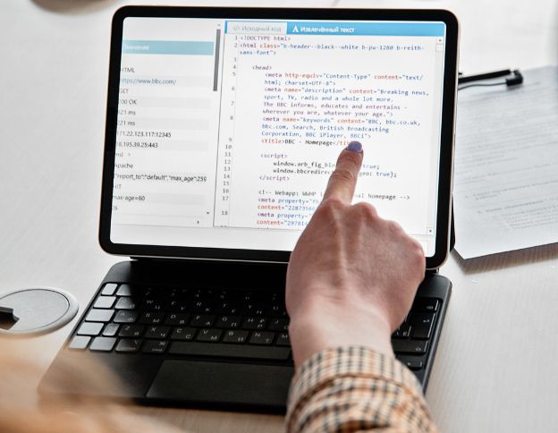 Person coding HTML on a tablet for web development.