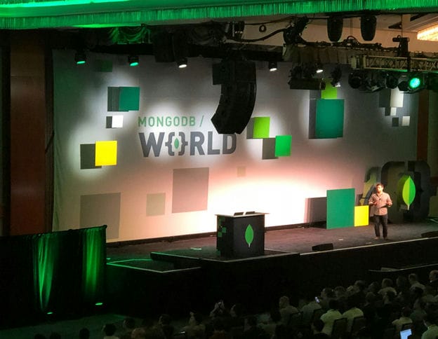 MongoDB World conference stage with colorful geometric decor.