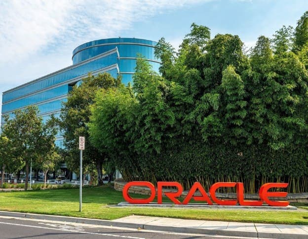 Modern Oracle Solutions office building with lush greenery and a prominent Oracle sign.