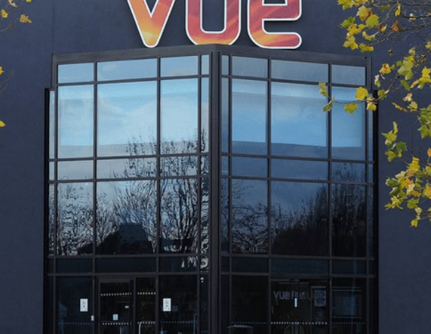 Modern glass building with Vue.js signage reflecting trees and sky.