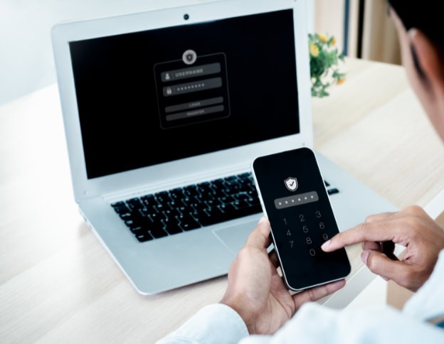 Person entering password on smartphone with laptop, cybersecurity focus.