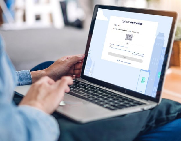 Person using a laptop with CyberArk identity management software on screen.