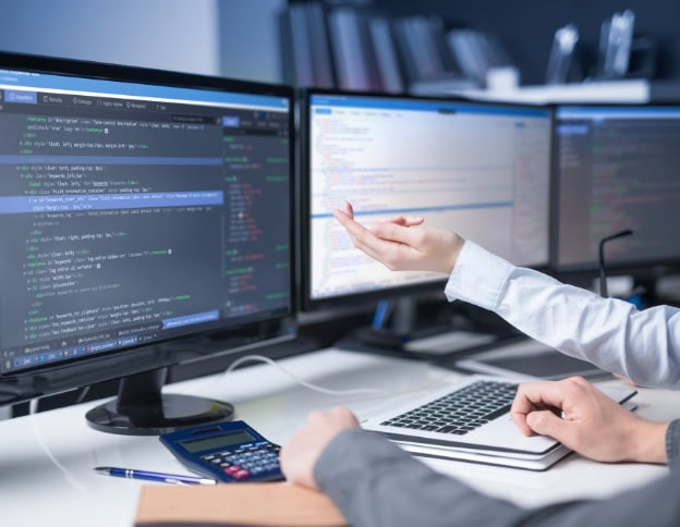 Software developer working on AI and ML coding for NLP projects on dual monitors.