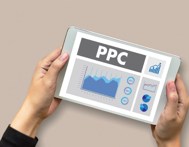 Hand holding tablet displaying PPC analytics and graphs for digital advertising.