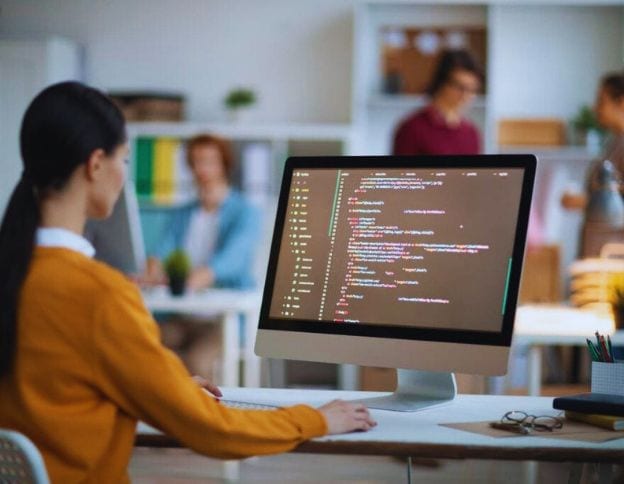 Developer working on CI/CD tools on computer in a modern office setting.