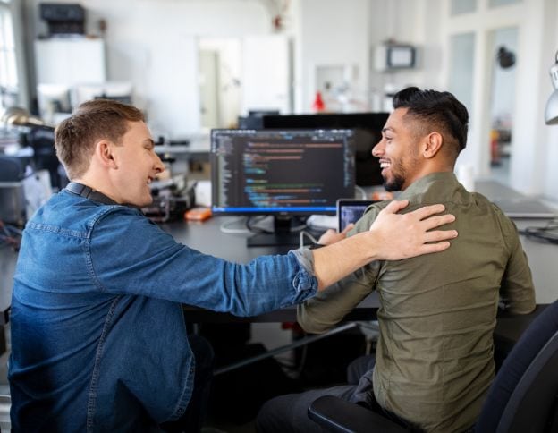 Two developers collaborating and communicating in a tech office.