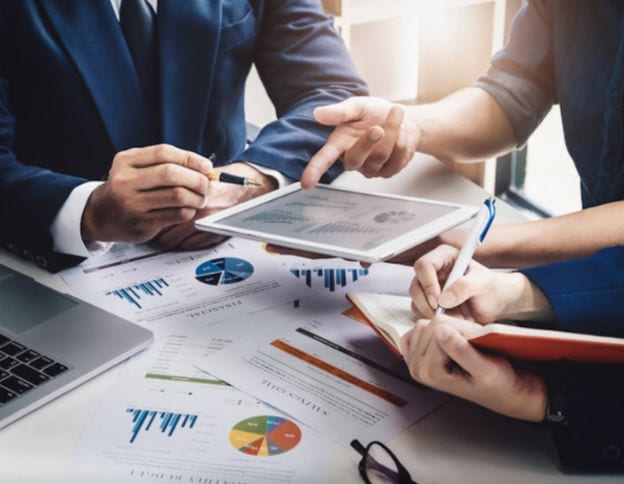 Business professionals discussing strategy with digital tablet and reports.