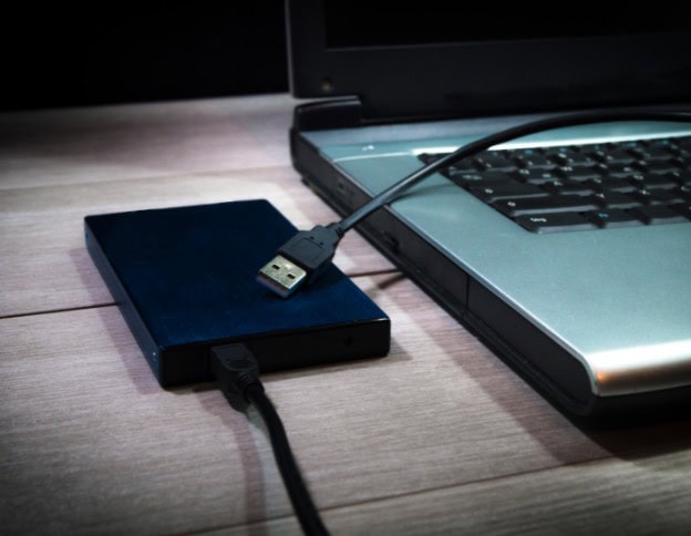 External backup drive connected to a laptop for secure data backup and recovery solutions.