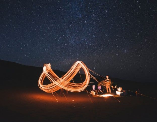 DevOps team working under starry night sky with light painting effects.