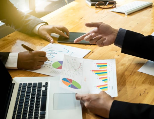 Two professionals discussing GraphQL implementation with charts and devices on a wooden table.