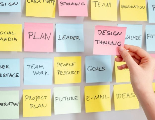 Collaborative brainstorming with colorful sticky notes on a wall for innovation and design thinking.
