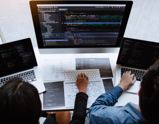 Developers working on cloud security tools on multiple screens.