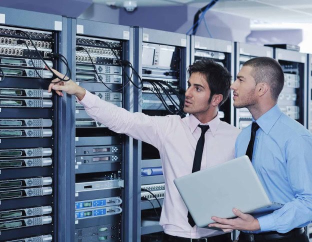 Two IT professionals working on network servers in a data center.