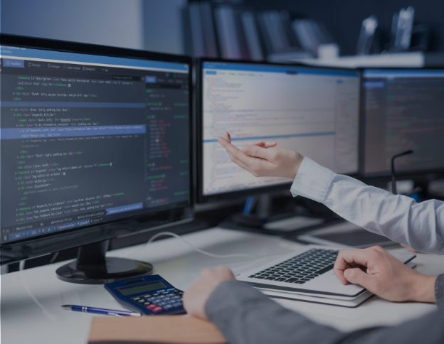 Software developer working on mobile app code on dual monitors.