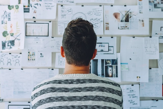 Man analyzing research data on a wall of charts and notes at Softinator TechLabs.