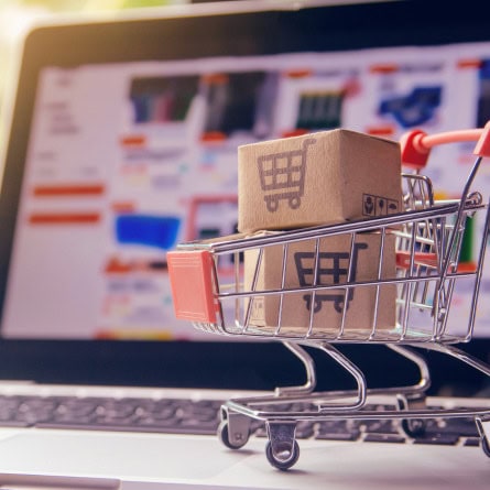 Small shopping cart with a cardboard box on a laptop keyboard.