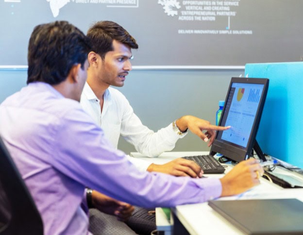 Two professionals analyzing data on a computer screen for AI-enhanced CRM services.
