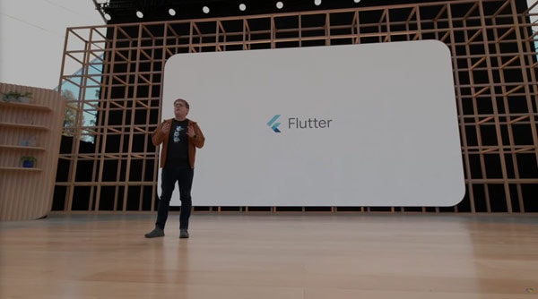 Developer presenting Flutter app on stage at Softinator TechLabs event.