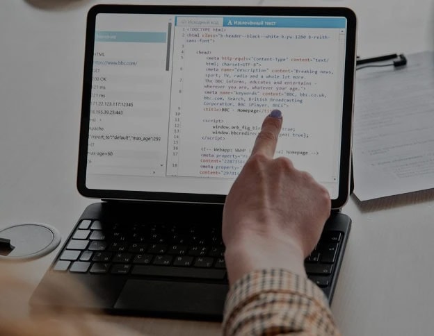Person coding HTML on a tablet for web development projects.
