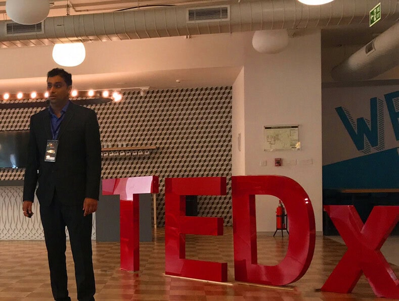 Man standing next to TEDx sign at Softinator TechLabs event.