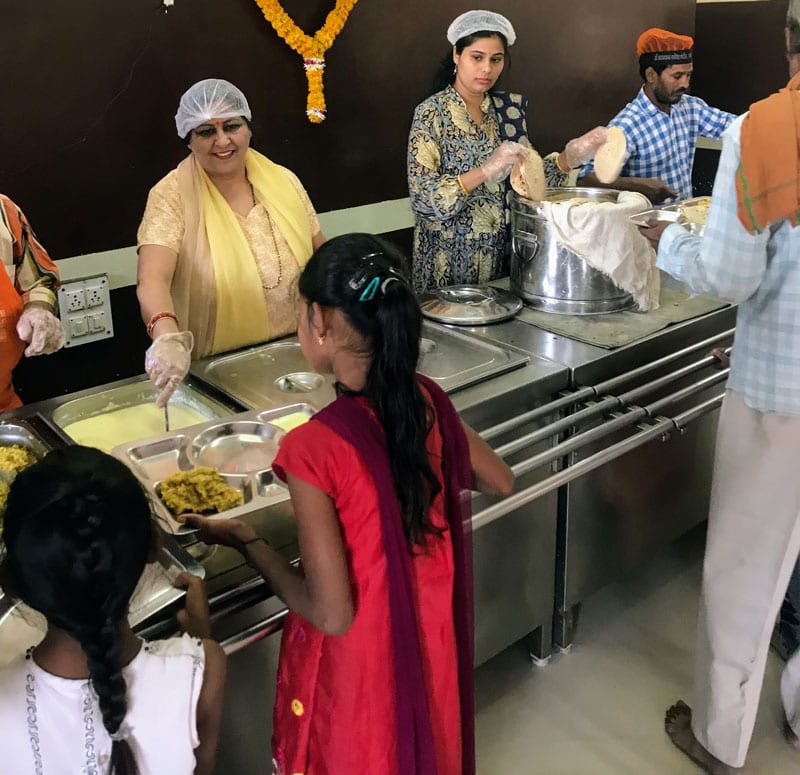 Women serving food to children at a community kitchen event.