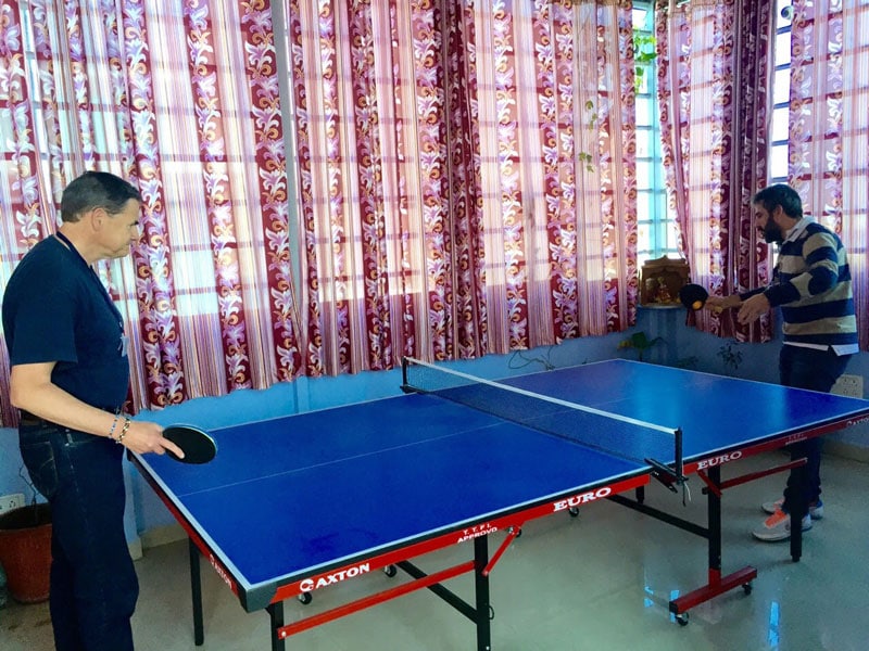 Table tennis game with two employees playing in a bright, modern office setting.